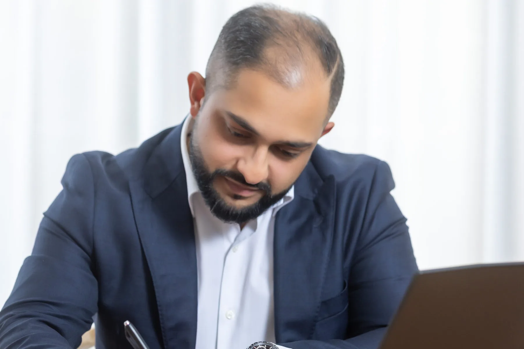 Manraj Singh making notes beside his laptop
