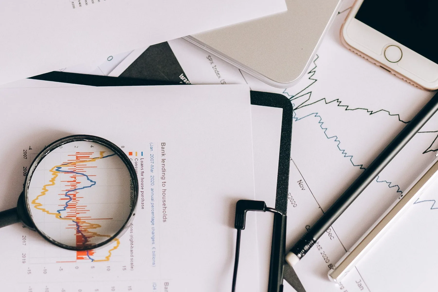 Laptop, printed charts and a magnifier laid out on a desk