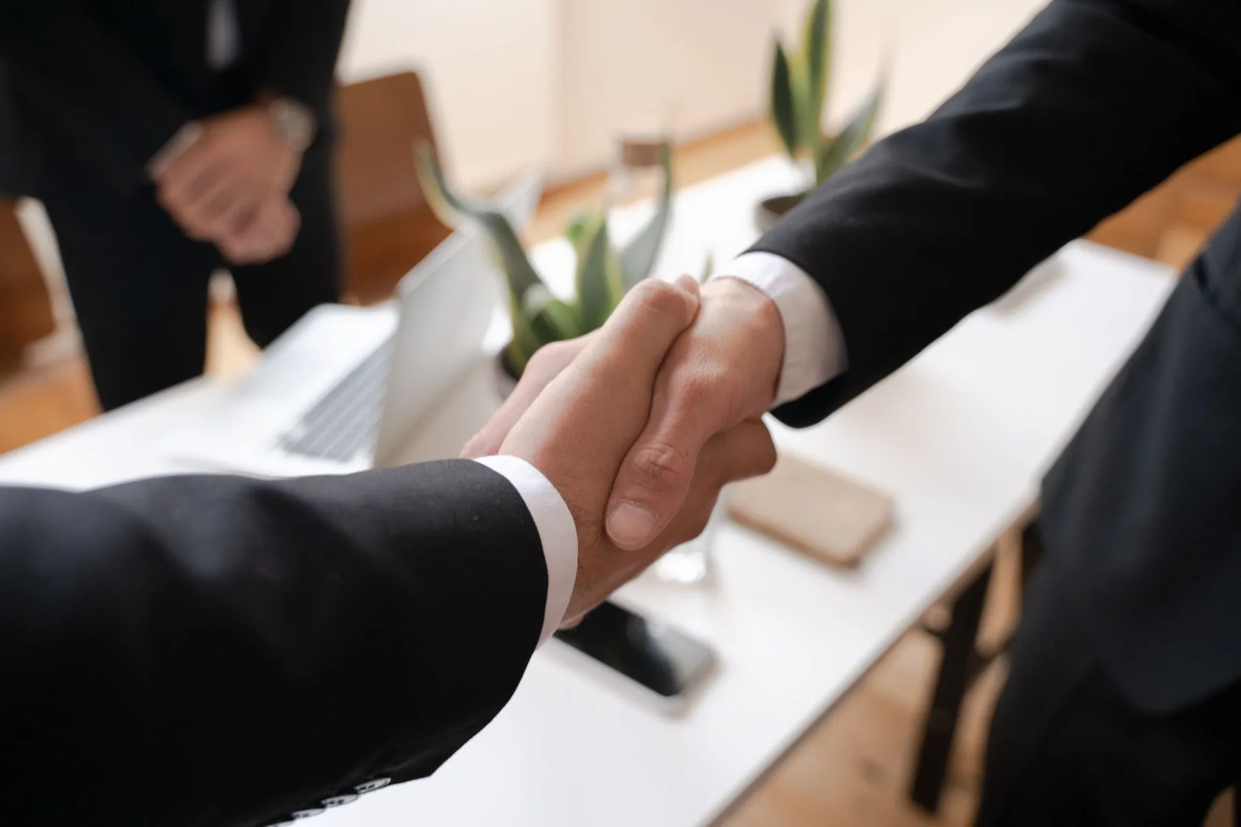 Two people shaking hands across a desk after a meeting