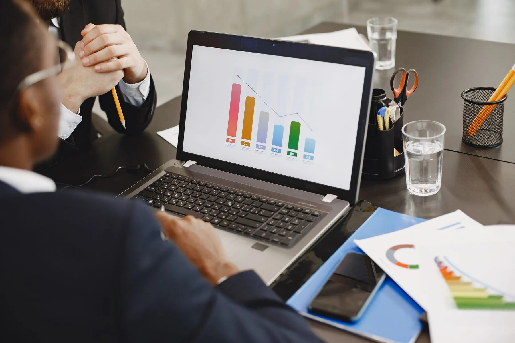 Two people reviewing a bar chart on a laptop in a meeting